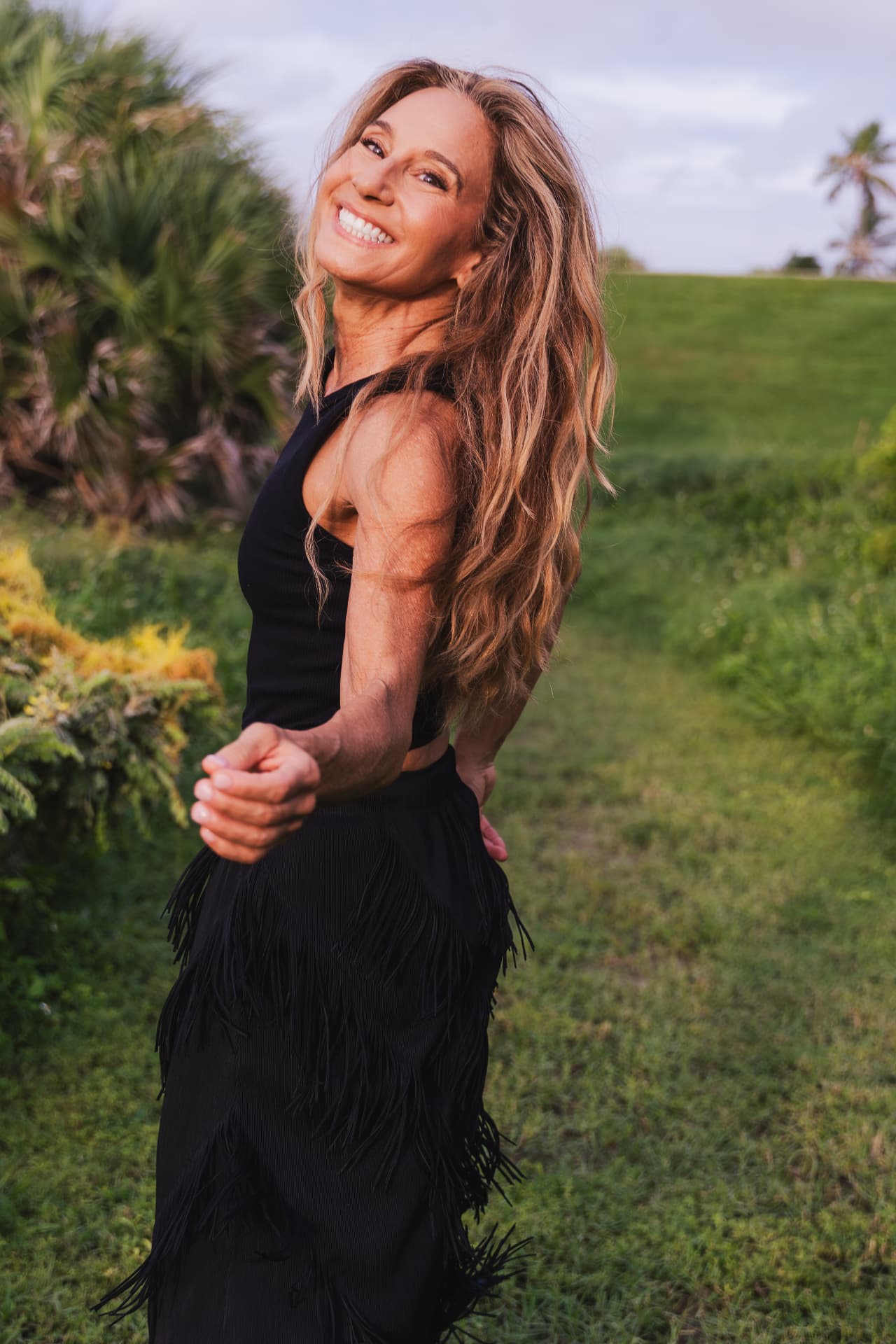 Nora Day smiling over her shoulder on a sunlit lawn at golden hour